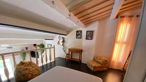 A room with a large bed, a small table, a chair, and a balcony with plants. - Studio Loft 4 people, Pool, Port Barcarès (Le Barcarès)