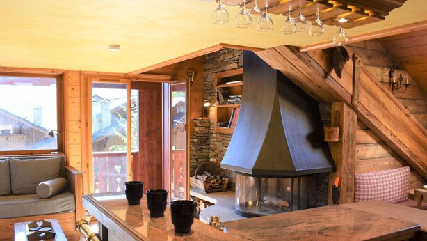 A cozy kitchen with a stone wall, wooden beams, and a large stove.