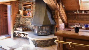 A cozy room with a stone fireplace, wooden shelves, and a bench.