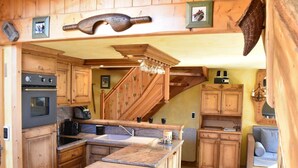 A rustic kitchen with wooden cabinets, a built-in oven, a sink, and a wooden island with a cutting board.