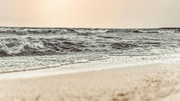 Een strand met golven en een heldere lucht.