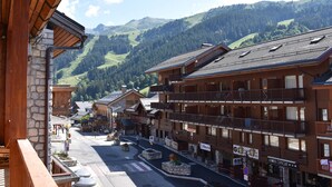 Eine Bergstadt mit Holzbauten, einer Straße mit Geschäften und Blick auf grüne Hügel.