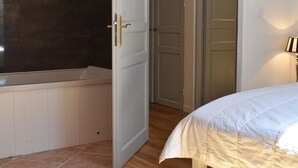 Ein Schlafzimmer mit einem weißen Bett, einer weißen Tür und einer Badewanne.