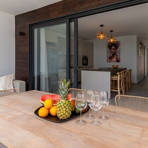 A dining area with a table set for four, featuring a fruit platter and wine glasses.