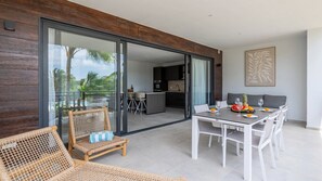 A modern outdoor dining area with a glass door leading to a kitchen and a pool view.