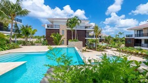 A resort with a swimming pool, palm trees, and modern buildings.