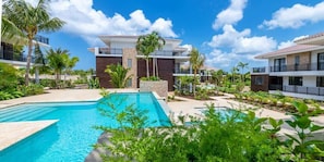 Un resort con piscina, palme e edifici moderni.