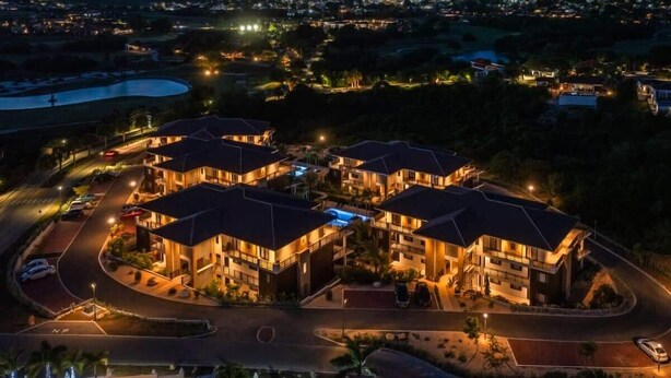 A multi-story hotel with a central courtyard, surrounded by roads and a body of water.