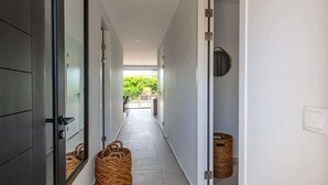 A hallway with a view to an outdoor balcony, a door with a mirror, and a basket on the floor.