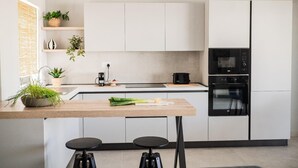 A modern kitchen with white cabinets, a black oven, and a coffee maker on the counter.