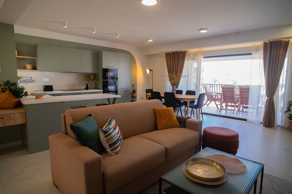 A modern living room with a sofa, coffee table, and a dining area with chairs and a table. - This apartment is a 2 bedroom(s), 2 bathrooms, located in San Pawl il-Baħar, null. (San Pawl il-Baħar)
