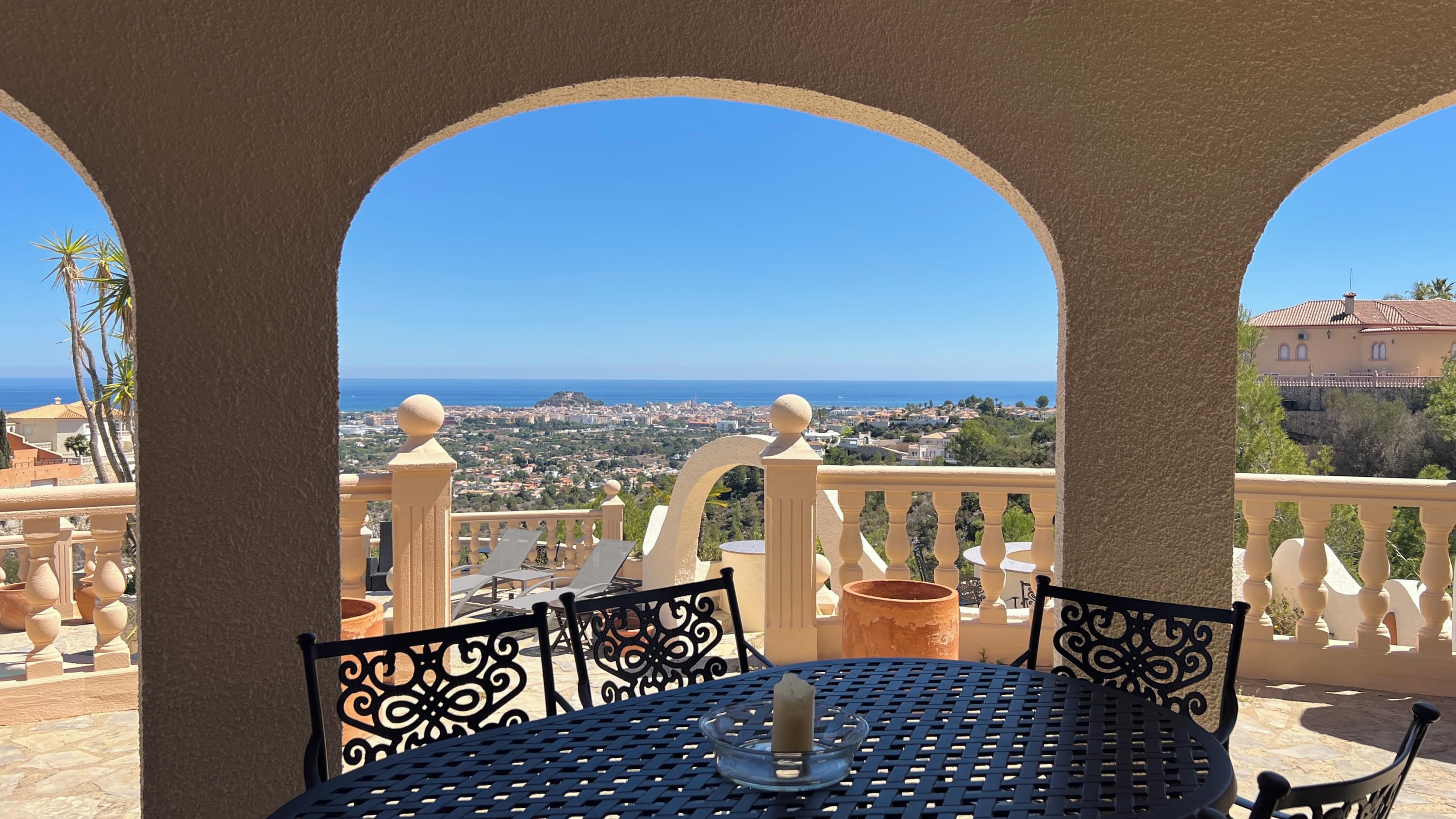 A terrace with a view of the sea, featuring a table with chairs and a candle.