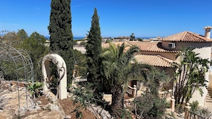 A Mediterranean-style villa with a terracotta roof, a stone archway, and a view of the sea.