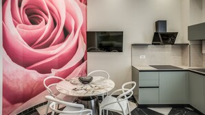 Een moderne keuken met een marmeren aanrechtblad, een ingebouwde kookplaat en een aan de muur bevestigde televisie.