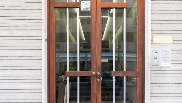 A wooden double door with glass panels, a metal handle, and a sign above the door.