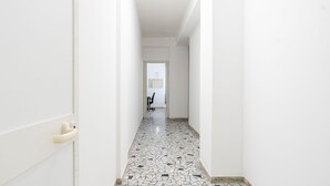 A narrow hallway with white walls and a tiled floor.