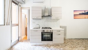 A modern kitchen with a built-in oven, a gas stove, and light wood cabinets.