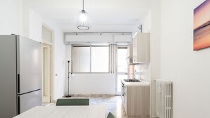 A compact kitchen with a refrigerator, stove, and a dining area with a table and chairs.