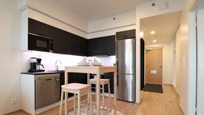 Una cocina moderna con lavavajillas, refrigerador y taburetes de bar.