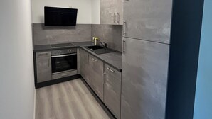 Eine moderne Küche mit grauen Schränken, einem eingebauten Ofen und einer schwarzen Arbeitsplatte.