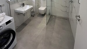 Ein modernes Badezimmer mit einer begehbaren Glasdusche, einem Waschbecken und einer Toilette.