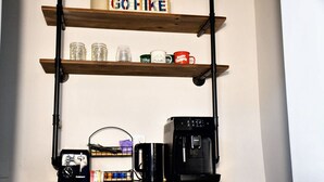 En köksbänk med en kaffebryggare, en mugg och en hylla med burkar och en mugg med texten ”UT OCH VANDRA”.