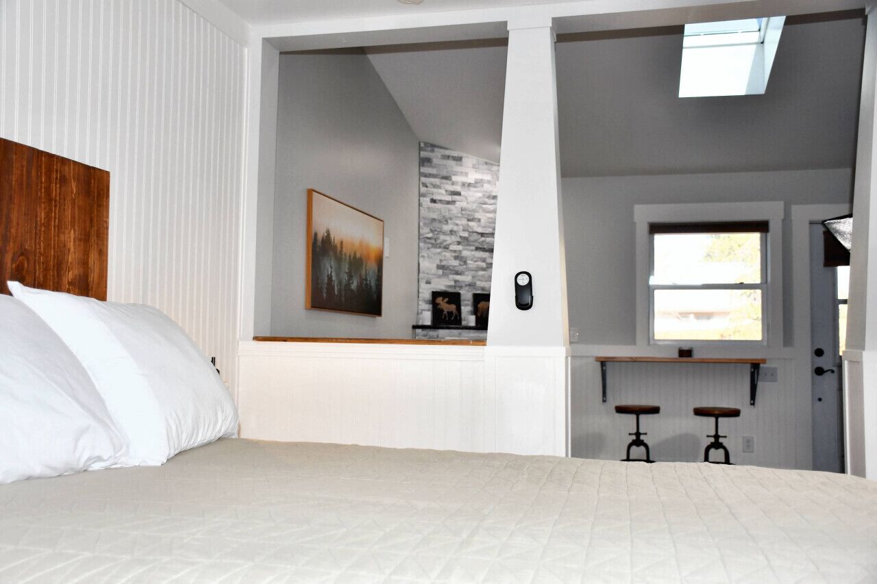 Un dormitorio con cama, un cuadro, una ventana y una pequeña zona de kitchenette.