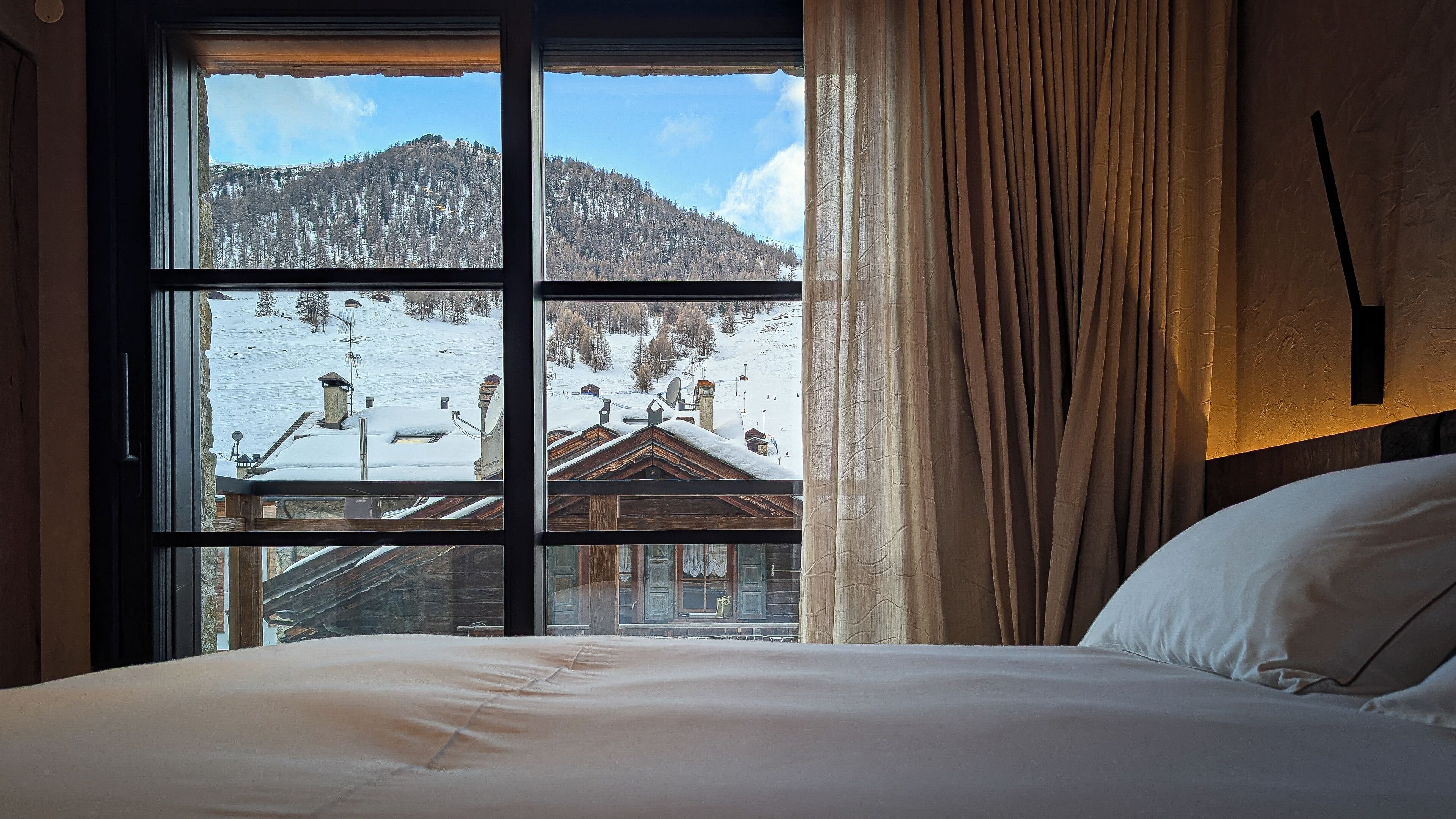 Habitación de hotel con un ventanal que ofrece vistas a un paisaje montañoso nevado.
