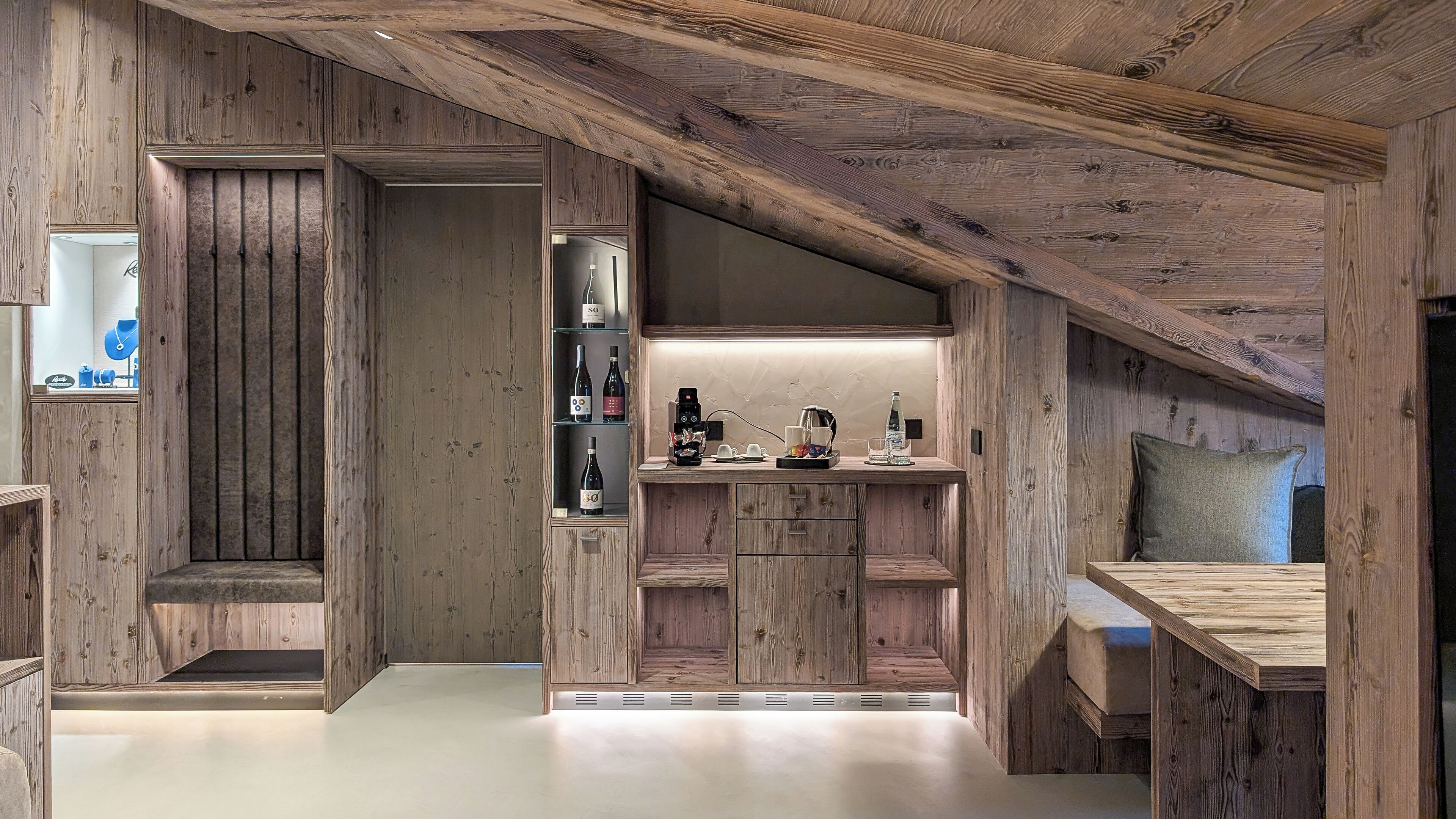 A rustic wooden interior with a kitchenette, built-in shelves, and a cozy seating area.