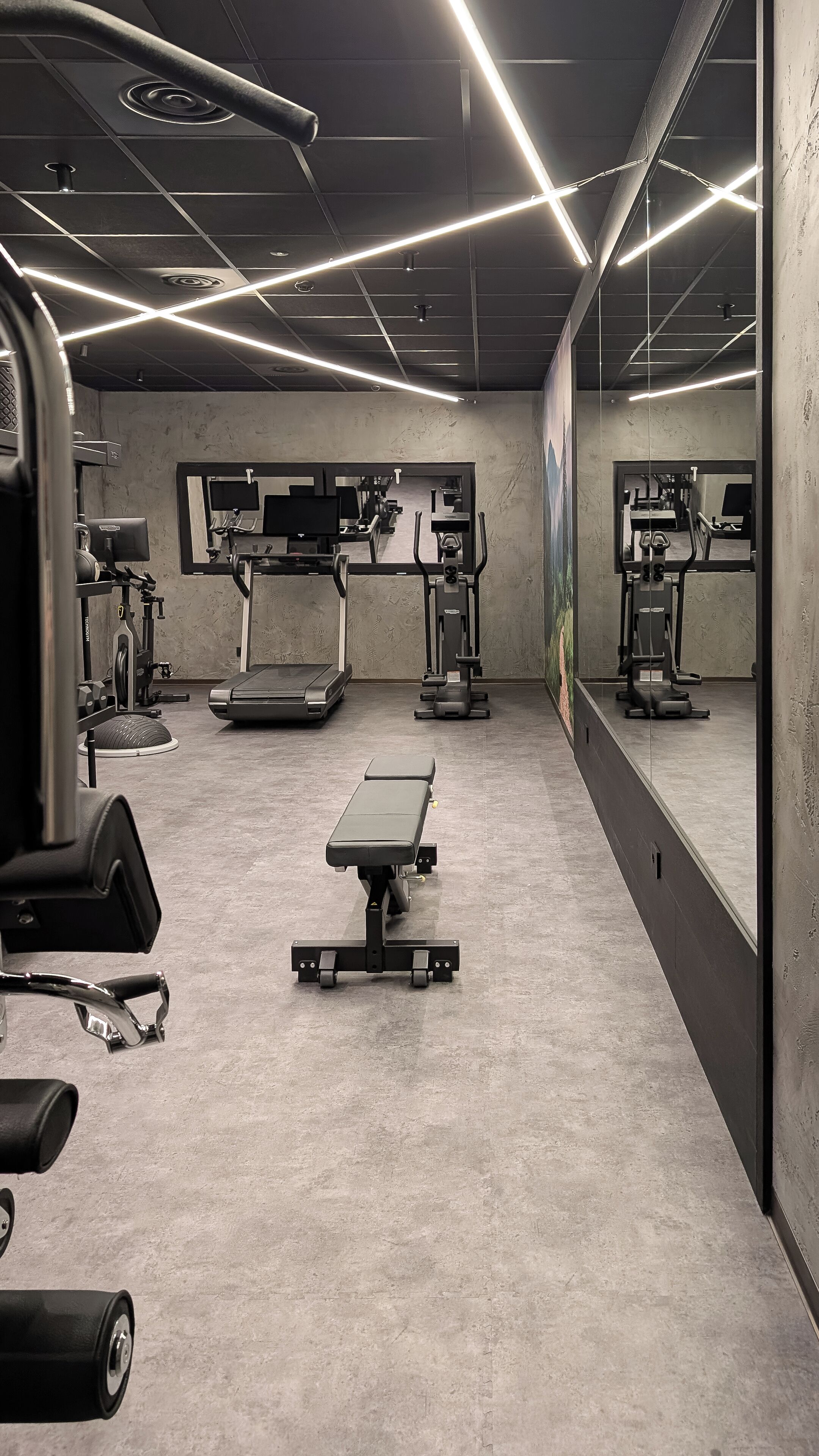 Una palestra con tapis roulant, macchinari ellittici e attrezzature per l'allenamento con i pesi.