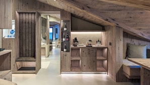 A rustic wooden interior with a kitchen area, wooden cabinets, and a bench.
