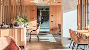 A modern hotel lobby with wooden paneling, a reception desk, seating areas, and a view into the hotel rooms.