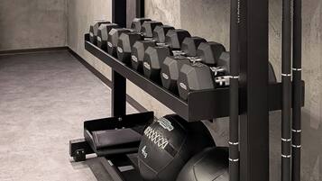 A gym with weightlifting equipment, including dumbbells and kettlebells, on racks.
