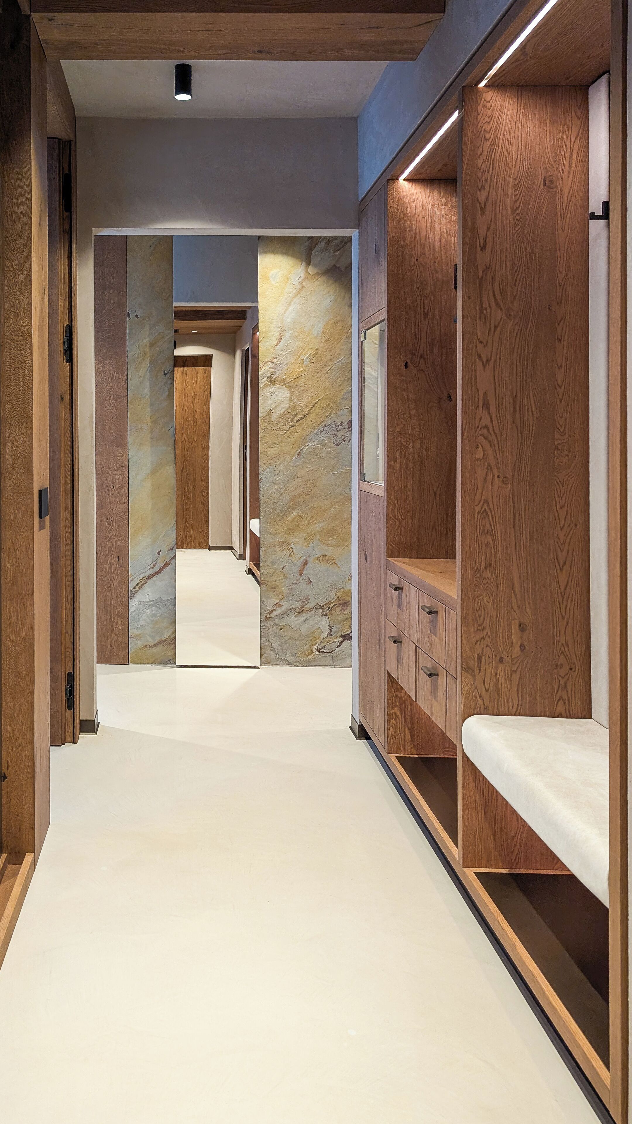 A hallway with wooden lockers and a marble wall.