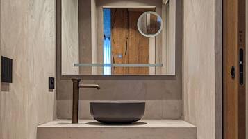 A modern bathroom with a large mirror, a vessel sink, and a wooden ceiling.