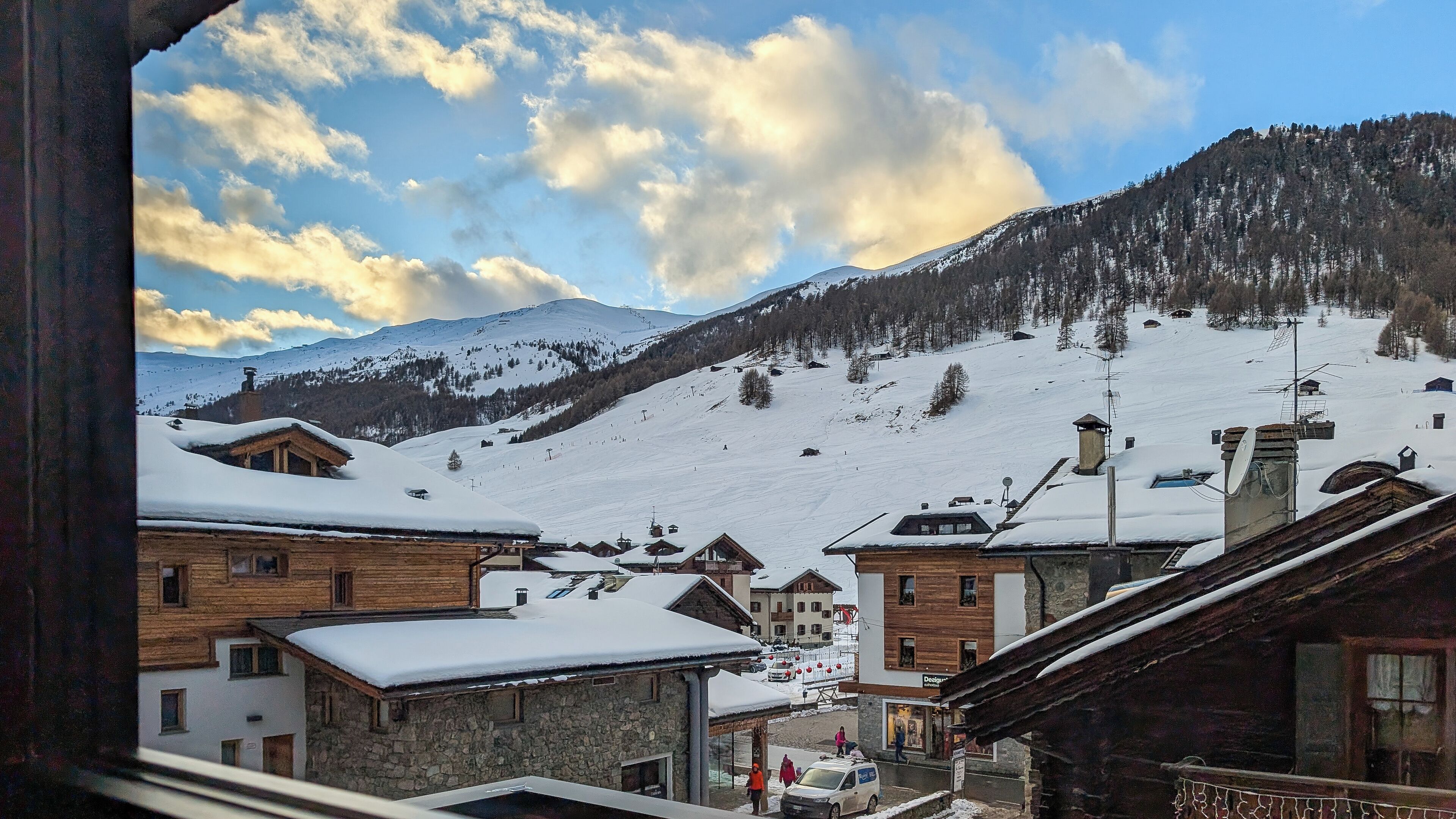 A snowy mountain village with wooden buildings and a ski slope in the background.