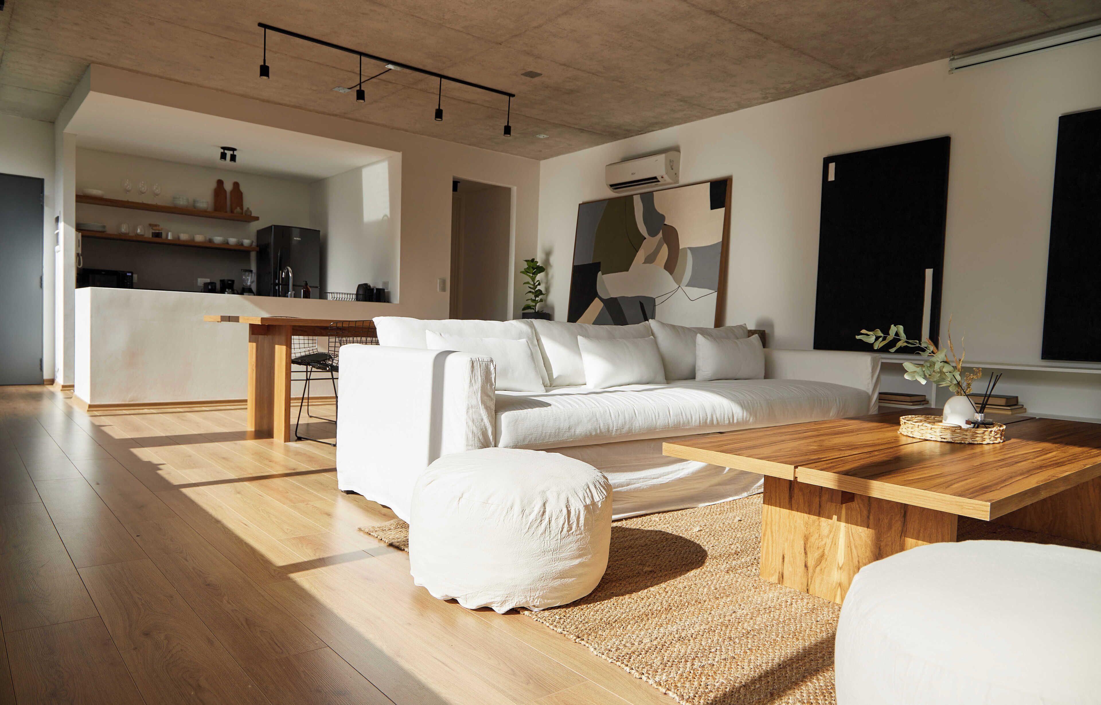 A modern living room with a wooden floor, white sofa, and a wooden coffee table.