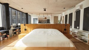 A modern bedroom with a large bed, wooden headboard, and a view of the kitchen through an open door. - Hestia at Gral. Las Heras 1700 (Buenos Aires)