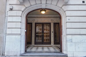 A grand entrance with a large arched doorway, a tiled floor, and a number plaque on the wall. - Hestia at Gral. Las Heras 1700 (Buenos Aires)