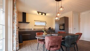 Una cucina moderna con zona pranzo, che include un tavolo rotondo, sedie e illuminazione a sospensione.