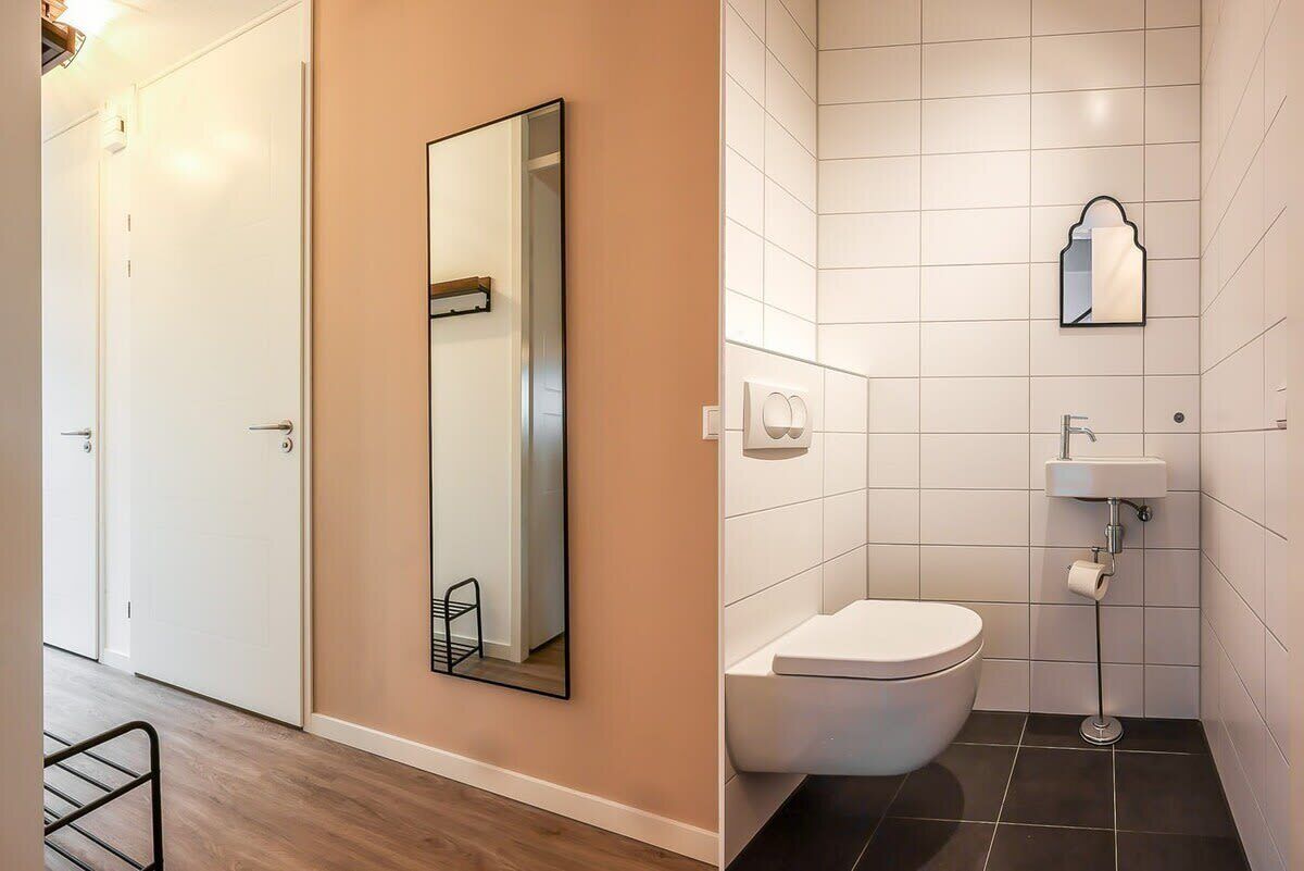 Un couloir avec une porte et un miroir au mur.