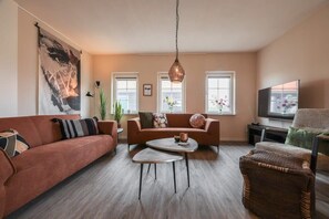 Ein modernes Wohnzimmer mit einer Couch, einem Couchtisch und einem Fernseher.