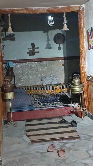 A room with a bed, a mat, a hanging lamp, and a small table with a teapot. - Gite ditabe tafoukte  (Imi N'Oulaoune)