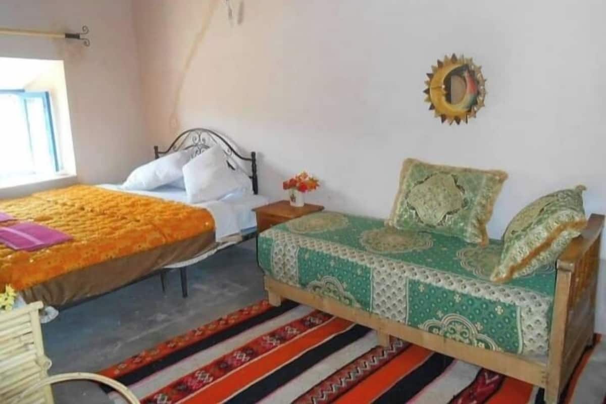 A bedroom with two beds, a window, and a decorative wall piece.