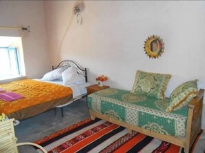 A bedroom with two beds, a window, and a decorative wall piece. - Gite ditabe tafoukte  (Imi N'Oulaoune)