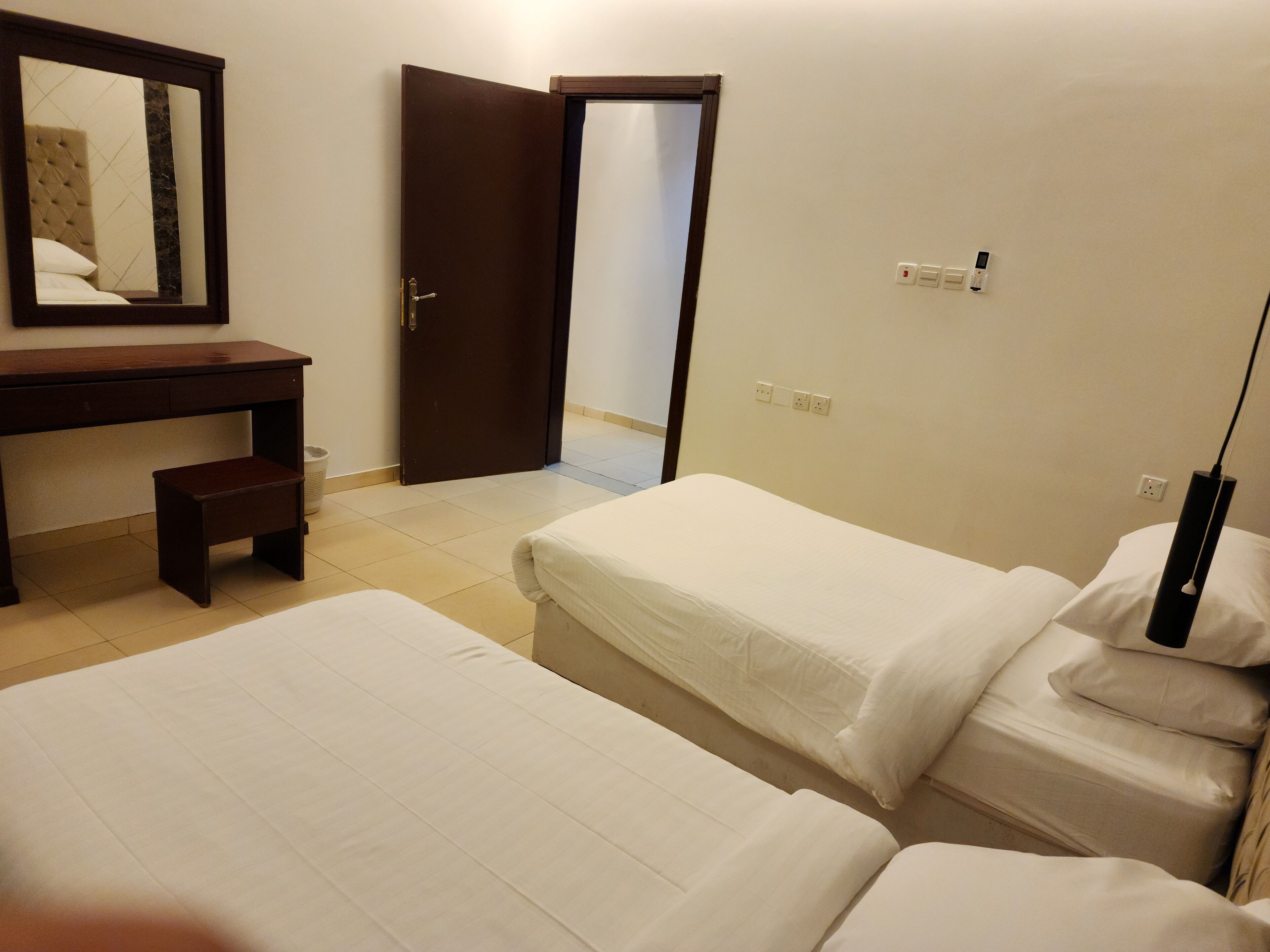 Habitación de hotel con dos camas, un escritorio y un espejo.