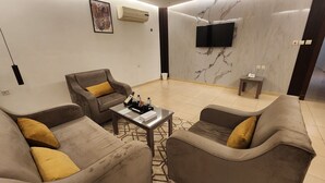 A modern living room with a sofa set, a coffee table, and a flat-screen TV mounted on the wall. - Afaq Suite Al- Shamisi - افاق سويت الشميسى (Riyadh)