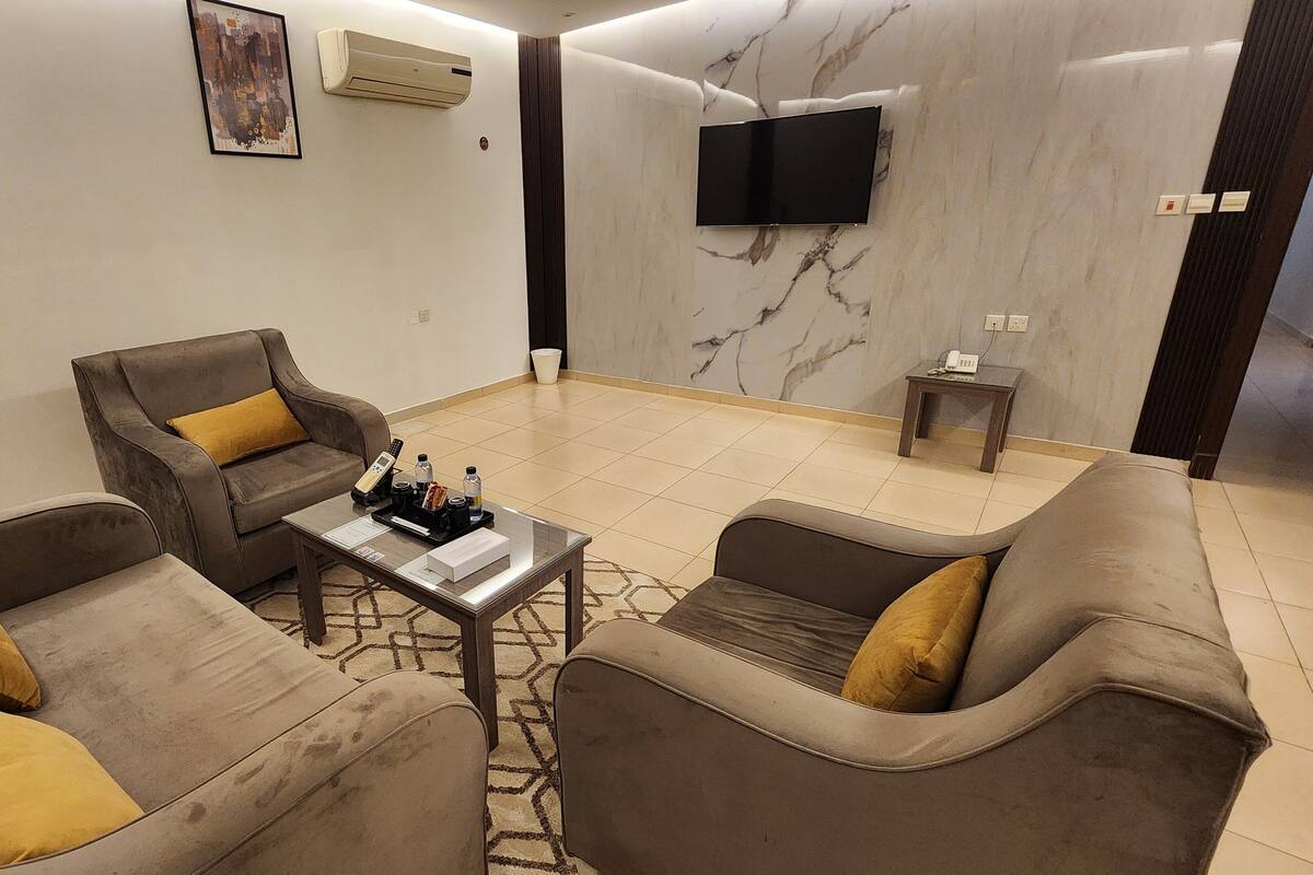 A modern living room with a sofa set, a coffee table, and a flat-screen TV mounted on the wall.