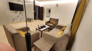 A modern living room with a sofa set, a coffee table, and a TV mounted on the wall. - Afaq Suite Al- Shamisi - افاق سويت الشميسى (Riyadh)