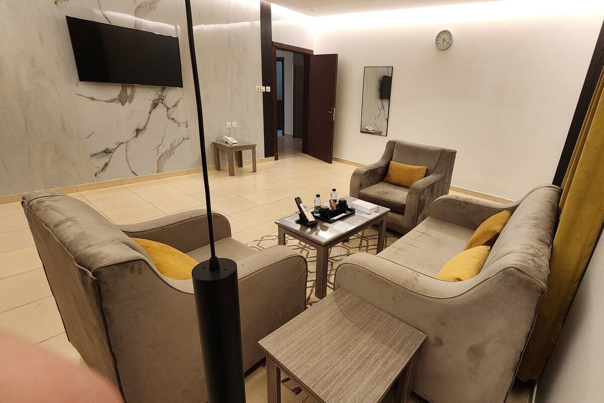 A modern living room with a sofa set, a coffee table, and a TV mounted on the wall.